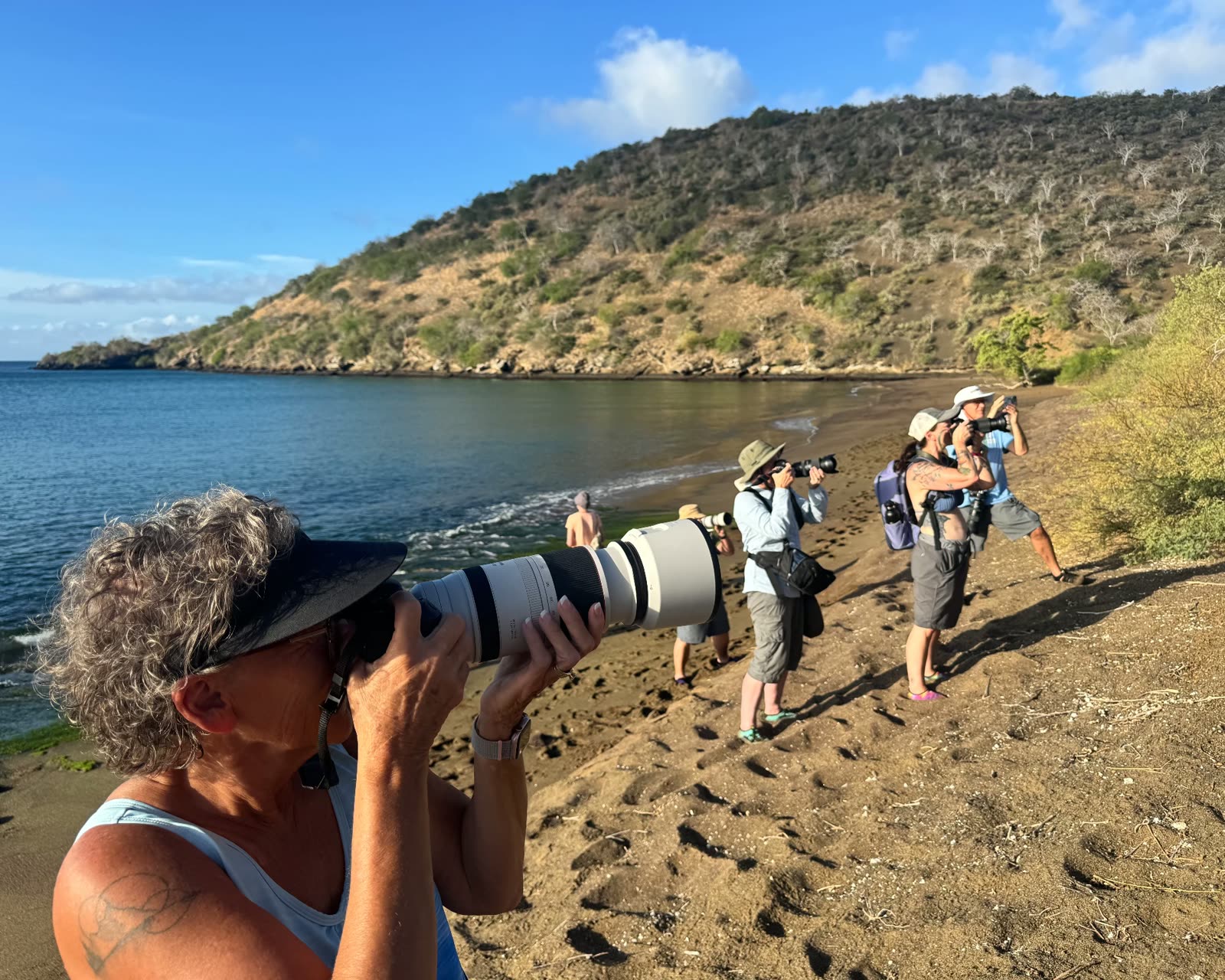 Guests photographing along a Galápagos beach at first light