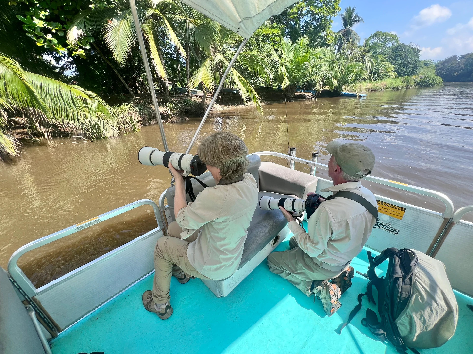 Two guests photographing wildlife from a boat on a jungle river