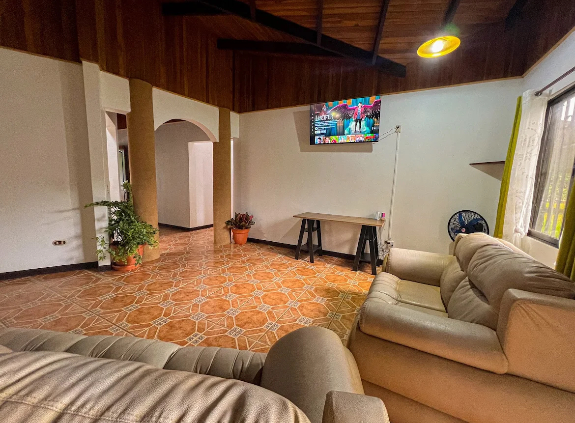 The open living room at the house, with sofas and a large TV under a timber-beamed ceiling